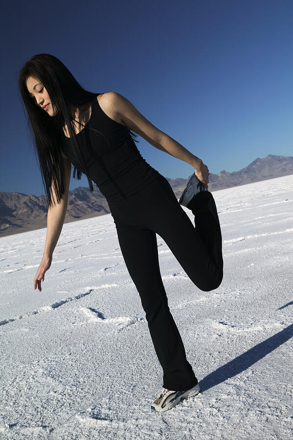 A Young Asian Woman Stretches And Works Out In The Barren Desert Environment Photograph by Photodisc