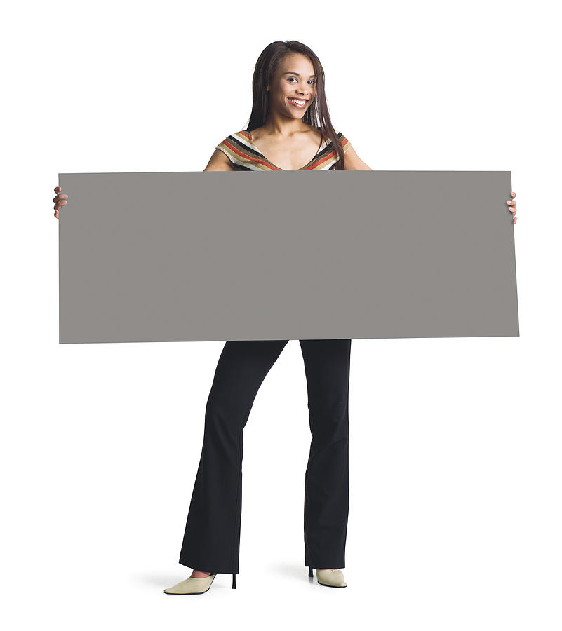 A Young Attractive African American Girl In Black Pants And Striped Blouse Holds A Blank Sign In Front Of Her With Both Hands Photograph by Photodisc