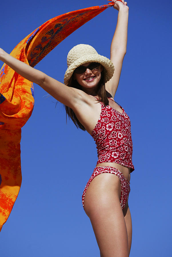 A Young Attractive Caucasian Female In A Swimsuit Hat And Sunglasses Walks And Plays At The Beach Photograph by Photodisc
