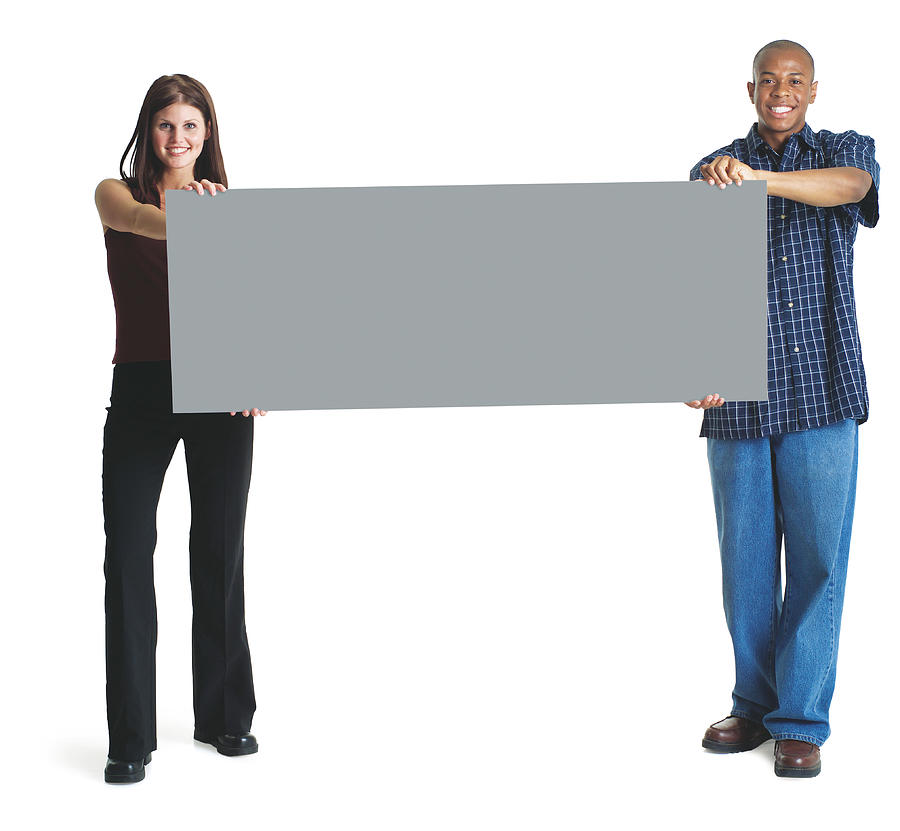 A Young Attractive Caucasian Woman And A Young African American Man Hold Up A Large Sign Together And Smile Photograph by Photodisc