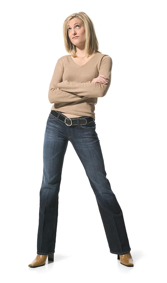 A Young Caucasian Blonde Woman In Jeans And A Tan Shirt Folds Her Arms And Glances Upward Photograph by Photodisc