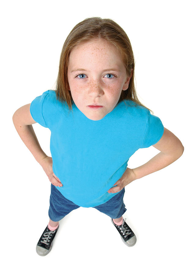 A Young Caucasian Girl In Jeans And Blue Shirt Puts Her Hands On Her Hips As She Frowns Up At The Camera Photograph by Photodisc