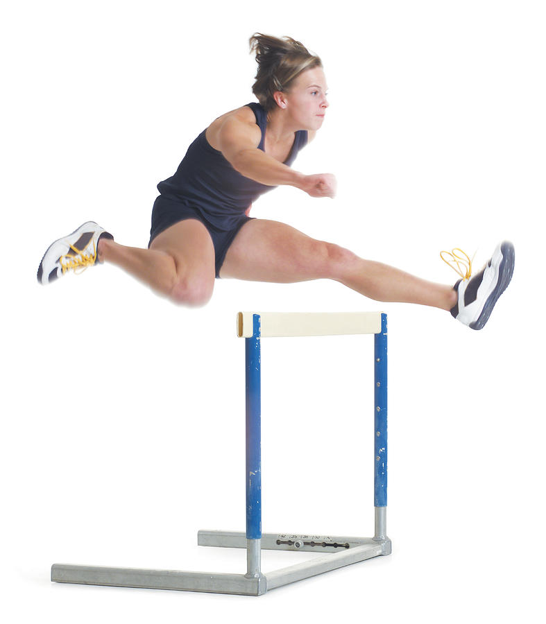 A Young Female Caucasain Runner Wearing A Black Uniform Is Jumping Over A Hurdle Photograph by Photodisc