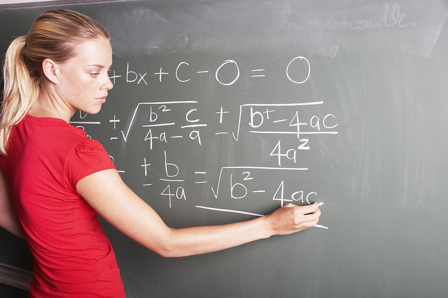 A young female student doing math at a chalkboard Photograph by OJO Images