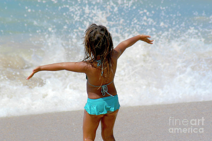 A young girl enjoying herself at the beach in the ocean spray. Photograph by Gunther Allen