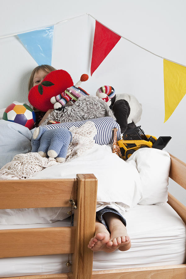A young girl lying on a bunk bed covered in stuffed toys Photograph by Halfdark