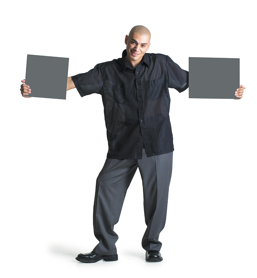 A Young Hispanic Male Wearing Grey Slacks And A Black Shirt Stretches His Arms Out To Hold Two Blank Signs As He Smiles At The Camera Photograph by Photodisc