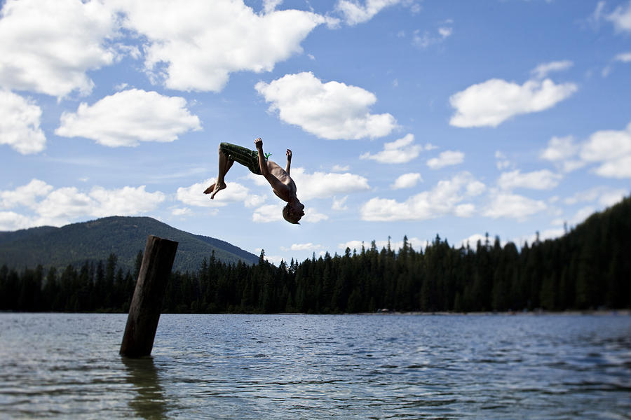 A young man backflipping off a pier at a lake in Idaho. Photograph by Patrick Orton