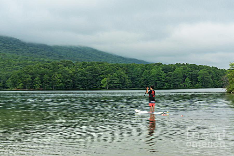 A young man uses a stand-up paddleboard on Lake Habeeb at Rocky Gap State Park in Flintstone, Maryland Photograph by William Kuta