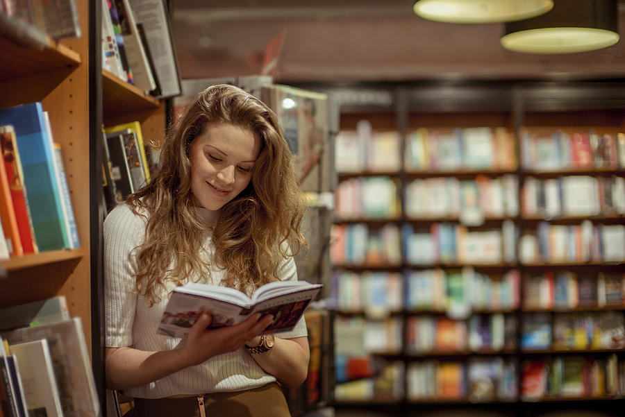 A young woman browses in a book store Photograph by Loop Images