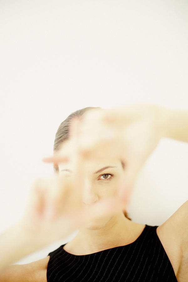A young woman framing part of her face with hands showing her left eye Photograph by Image Source