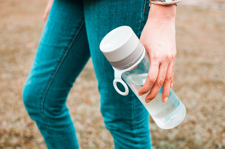 A young woman is holding a reusable water bottle container outdoors Photograph by Karl Tapales
