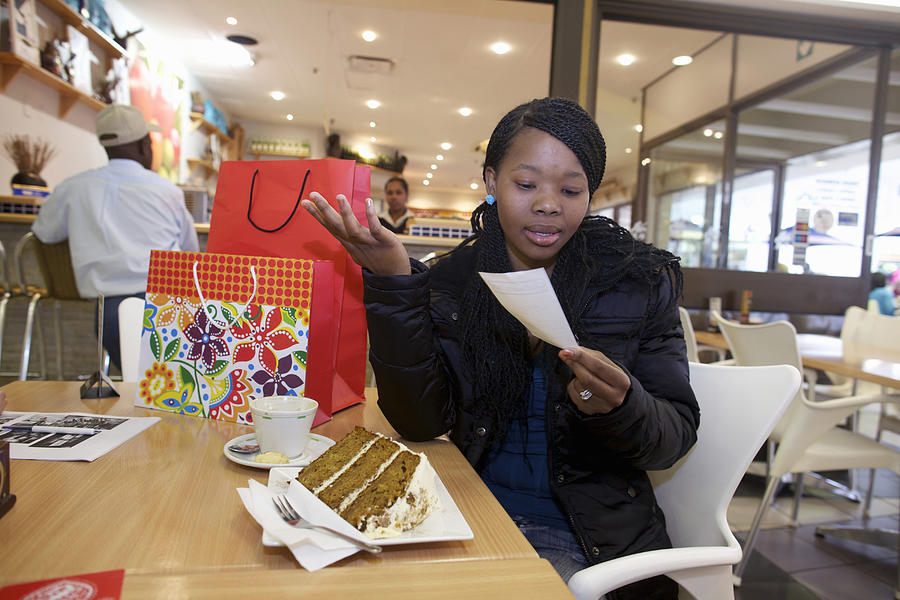 A young woman looking at the bill while sitting at a coffee shop. Pietermaritzburg, KwaZulu-Natal, South Africa Photograph by Heinrich van den Berg