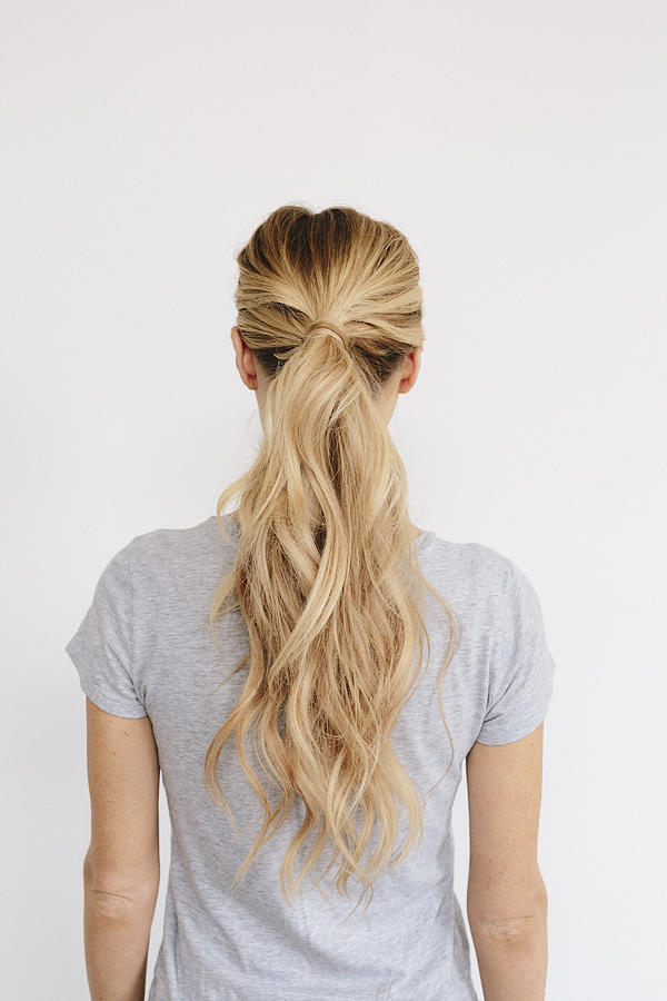 A young woman with long blond wavy hair tied in a ponytail. Back view. Photograph by Mint Images