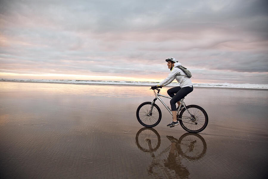 A young women riding her bike on the beach. Photograph by Adam Hester
