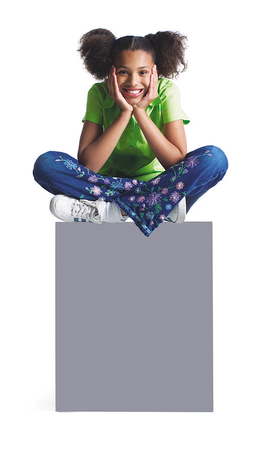 A Younng African American Girl In Jeans And A Green Shirt Sits With Her Legs Crossed Atop A Blank Sign Photograph by Photodisc