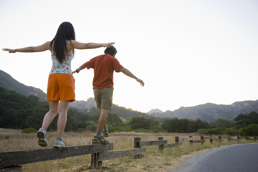 Active couple balancing on low fence. Photograph by Stewart Cohen