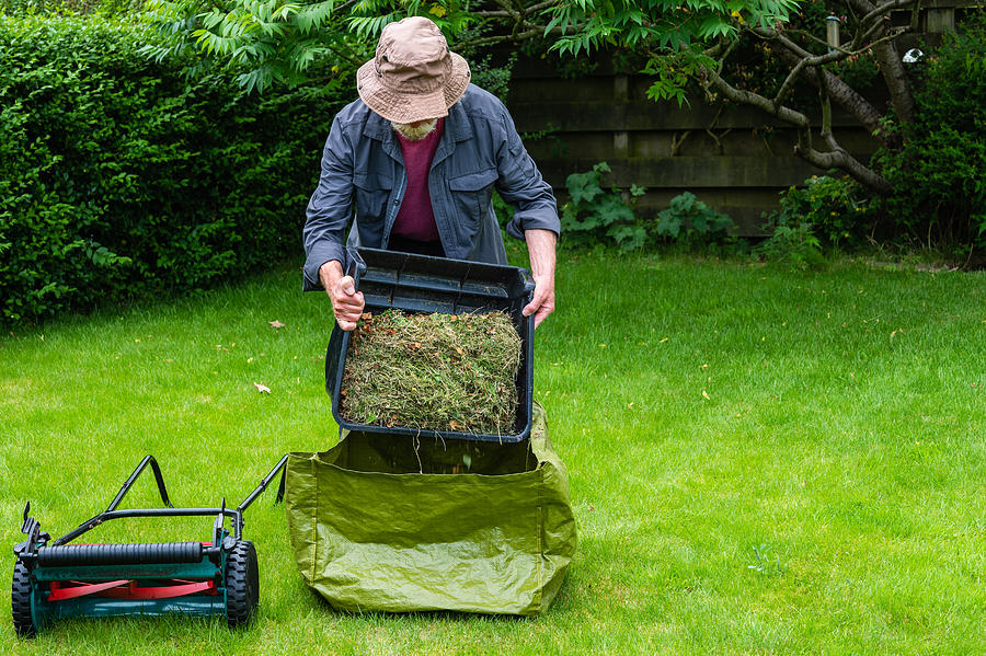 Active senior man emptying a grass box Photograph by JohnFScott