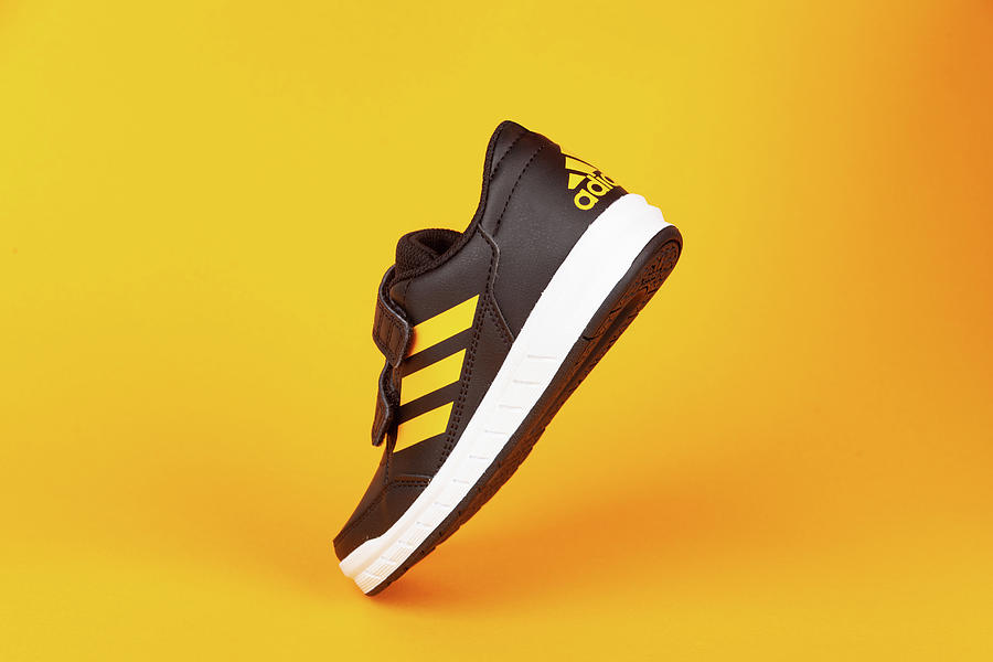 Sports Photograph - ADIDAS shoe on yellow background. Product shot. by Michael Dechev