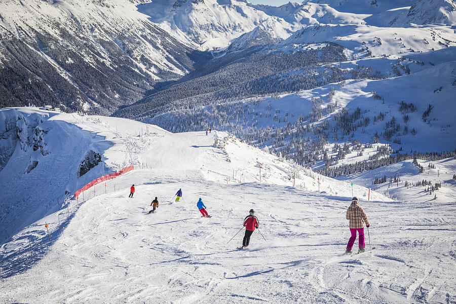Adult family skiing and snowboarding on sunny day. Photograph by VisualCommunications
