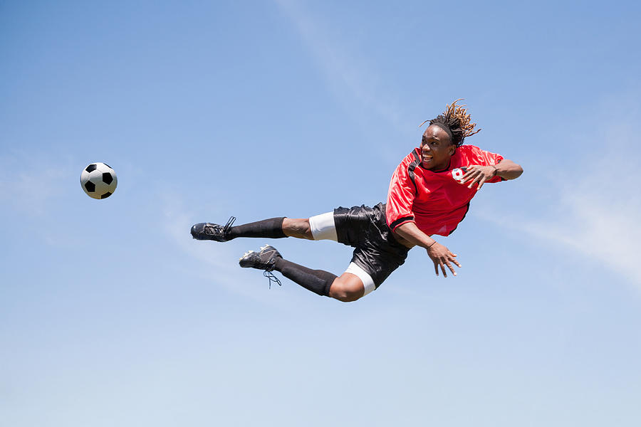 Adult soccer player kicking ball in mid-air during game Photograph by SDI Productions