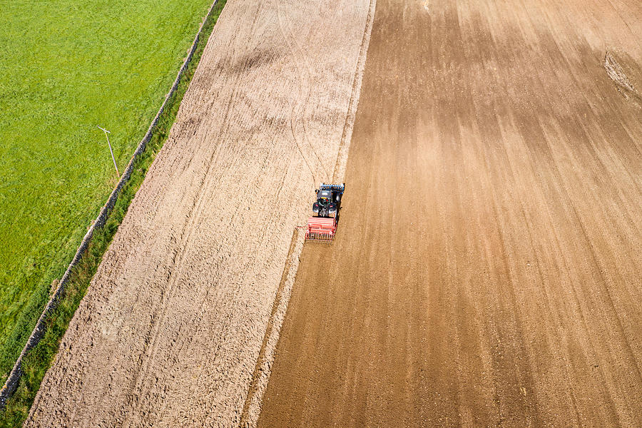 Aerial rear view of a tractor being used to pull a seed drill on a Scottish farm on a late summer day Photograph by JohnFScott