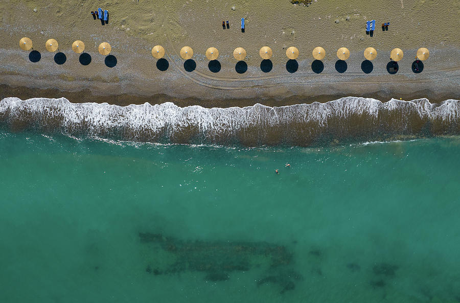 Aerial view from a flying drone of beach umbrellas in a row on a Photograph by Michalakis Ppalis