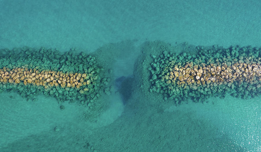 Aerial view from flying drone of crystal blue ocean water and sea wall. Photograph by Michalakis Ppalis