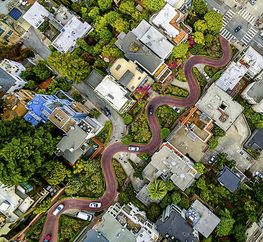Aerial view of a residential city area, with road descending a hillside with eight hairpin turns. Photograph by Mint Images