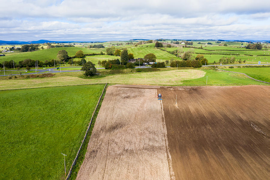Aerial view of a tractor being used to pull a seed drill on a Scottish farm on a late summer day Photograph by JohnFScott