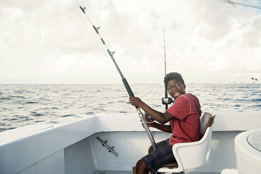 African-american boy on a sea fishing trip. Photograph by Martinedoucet