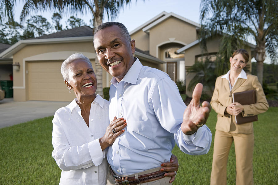 African American couple with real estate agent outside house Photograph by Kali9