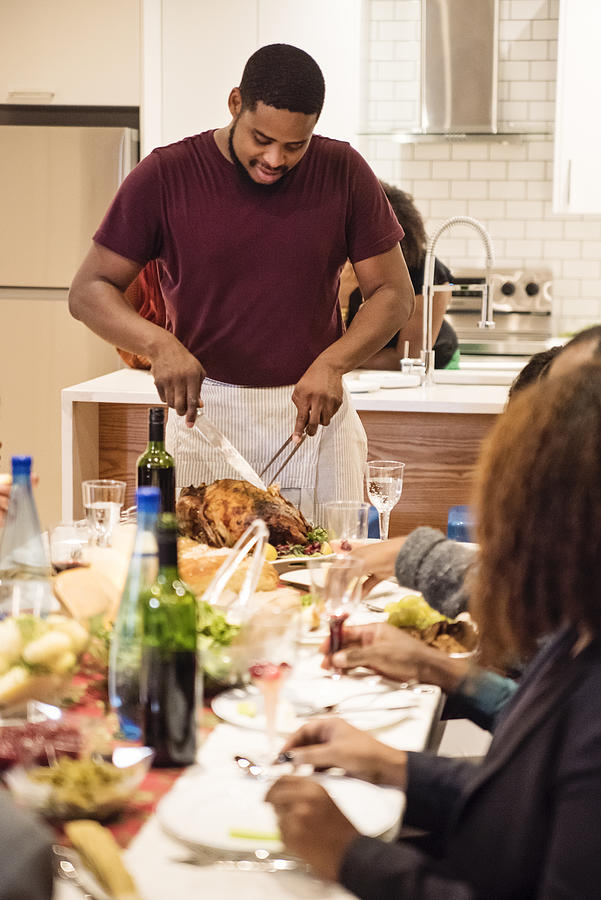 African-american man cutting turkey for Thanksgiving dinner. Photograph by Martinedoucet