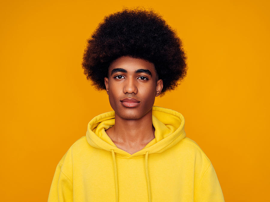 African american man with afro hair wearing hoodie and standing over isolated yellow background Photograph by CoffeeAndMilk