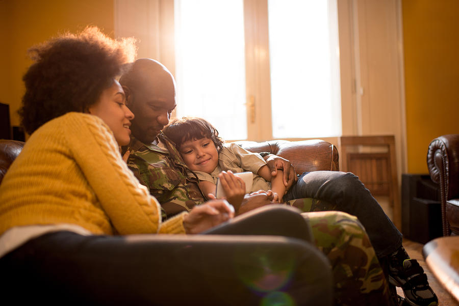 African American military family using cell phone at home. Photograph by BraunS