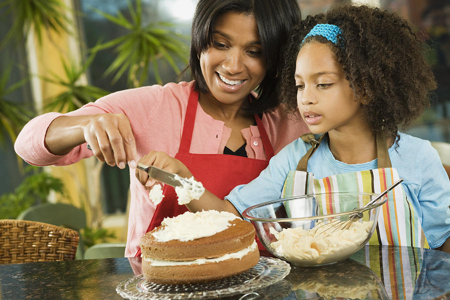 African American mother and daughter frosting cake Photograph by Jon Feingersh Photography Inc