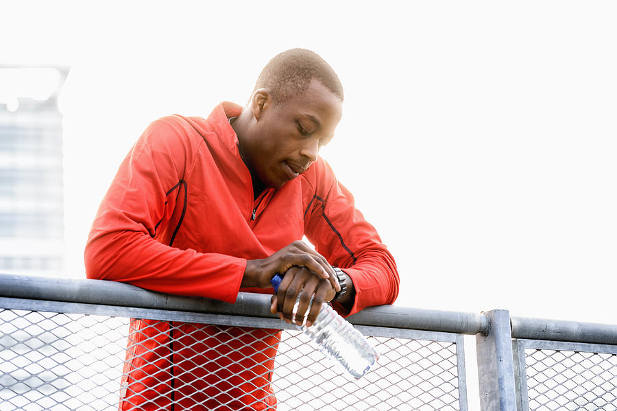 African American runner checking his watch on railing Photograph by Jacobs Stock Photography Ltd