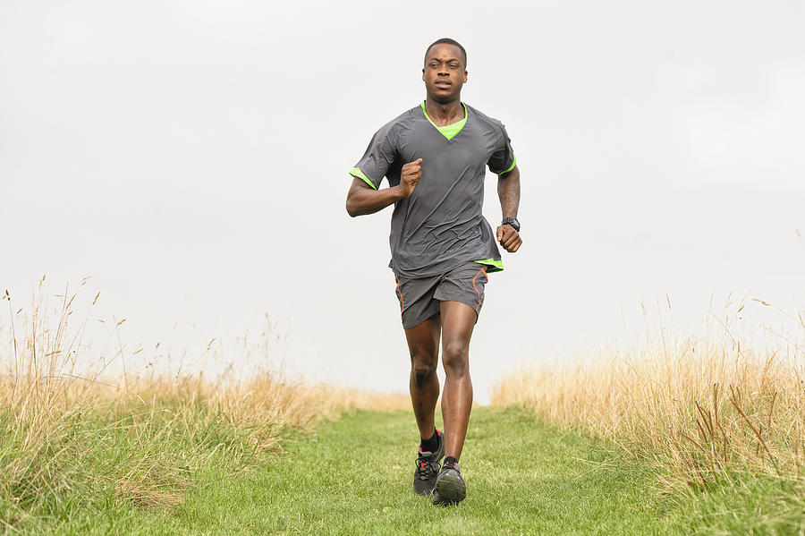 African American runner jogging in rural field Photograph by Jacobs Stock Photography Ltd