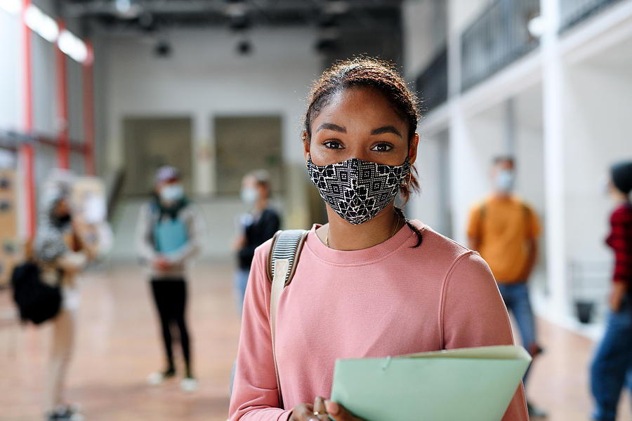 African-american student with face mask back at college or university, coronavirus concept. Photograph by Halfpoint