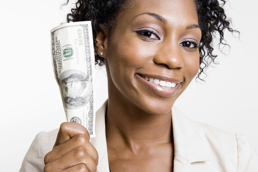 African American woman holding hundred dollar bill Photograph by Tanya Constantine