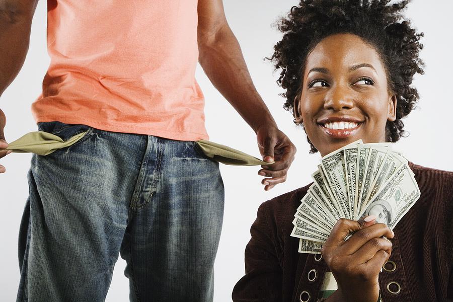 African American woman holding money next to man with empty pockets Photograph by Hill Street Studios