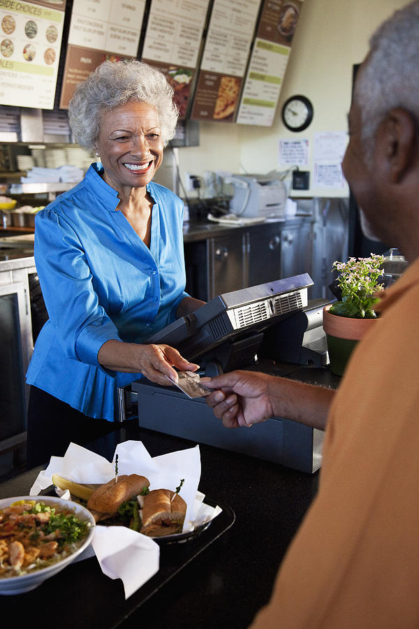 African American woman taking mans credit card in restaurant Photograph by Ronnie Kaufman