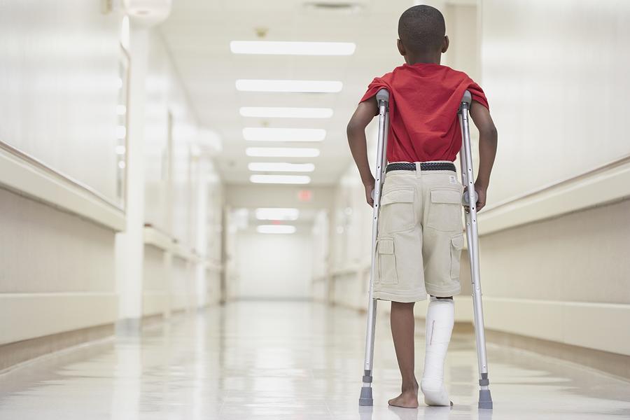 African boy with broken leg walking on crutches Photograph by ER Productions Limited