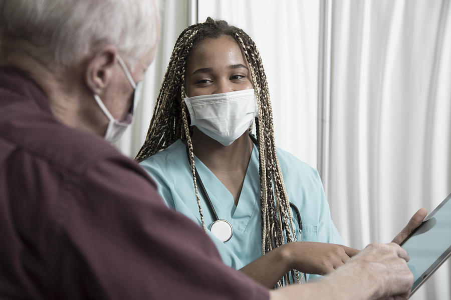 African descent doctor consults with Senior Caucasian patient. Photograph by LifestyleVisuals