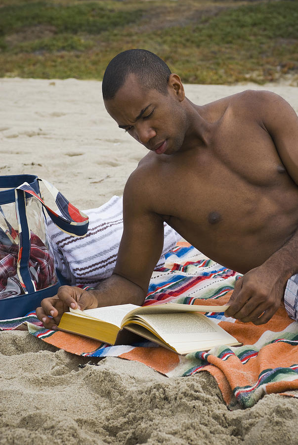 African man reading book on beach Photograph by Sam Bloomberg-Rissman