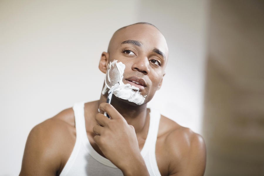 African man shaving face Photograph by Visual Ideas/Nora Pelaez