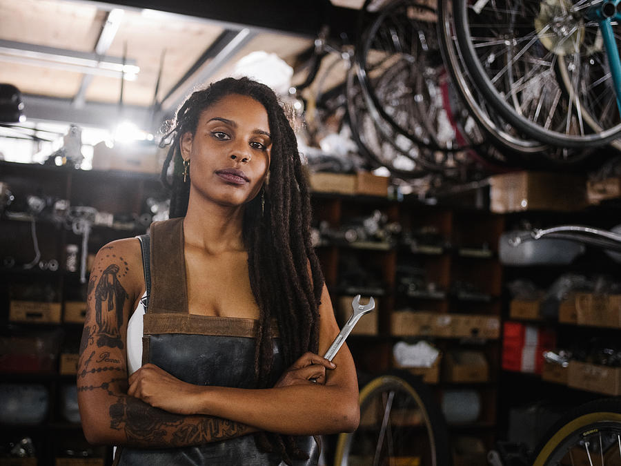 Afro woman bicycle mechanic looking proud in bike repair worksho Photograph by Wundervisuals