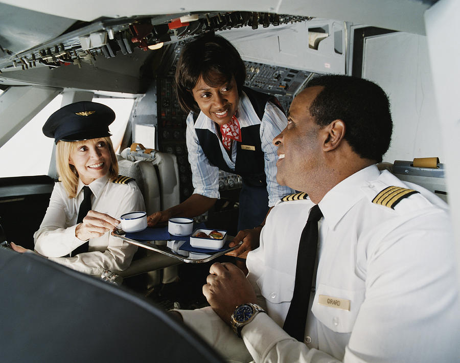 Air Hostess Serves Coffee to the Pilots in the Cockpit Photograph by Digital Vision.