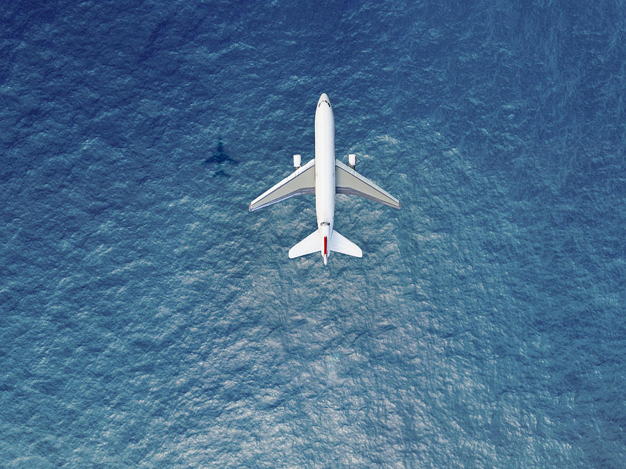 Airplane flies over a sea Photograph by  Orbon Alija