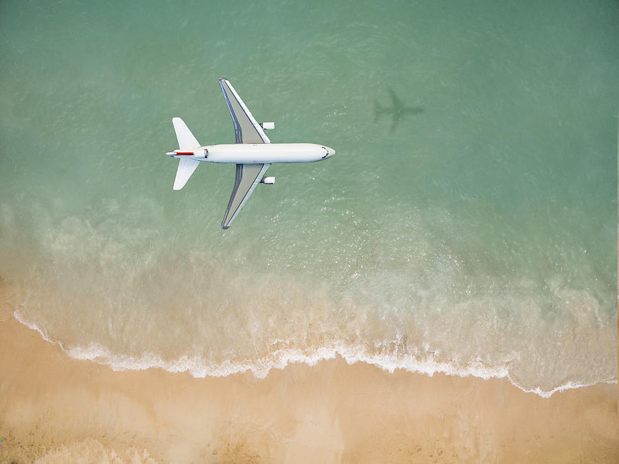 Airplane flying over the beach Photograph by Orbon Alija